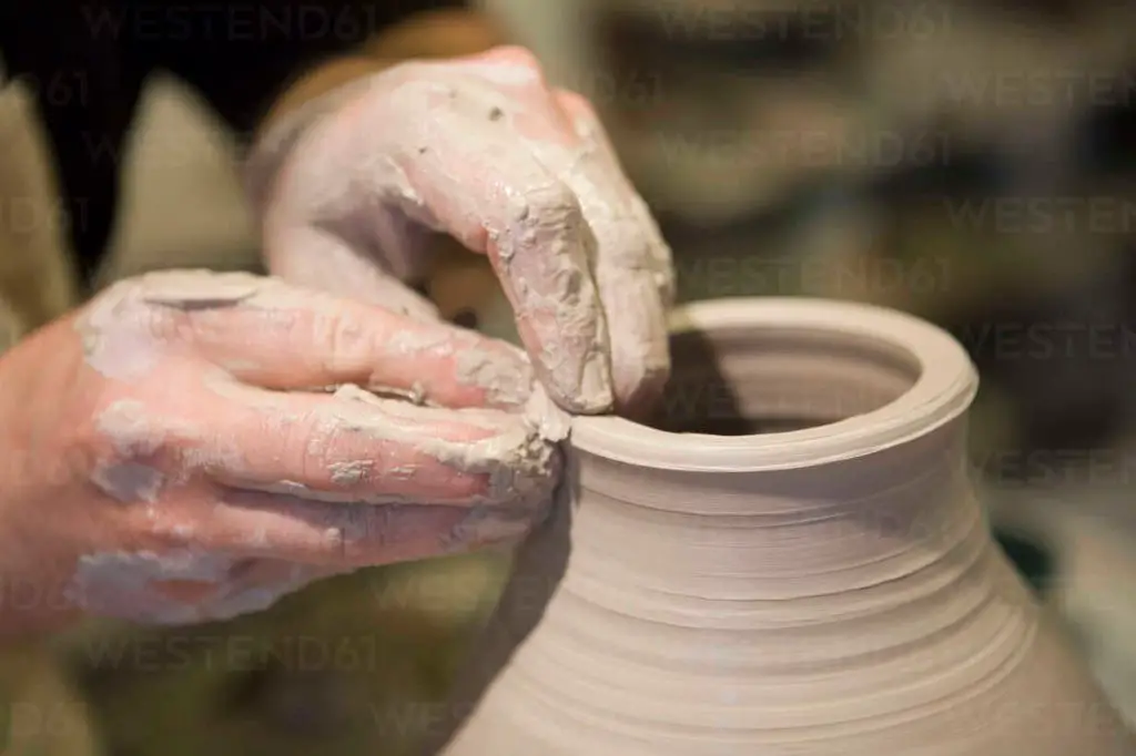 close up of potter's hands working on ceramic pot