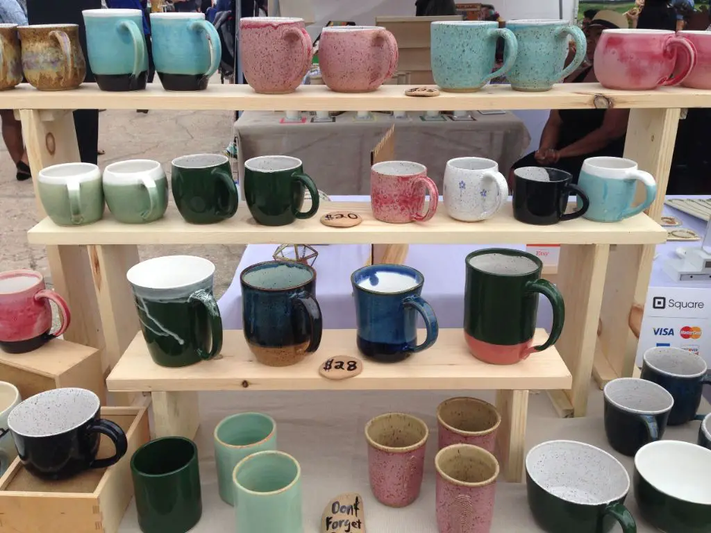 handmade pottery mugs for sale at a craft fair booth