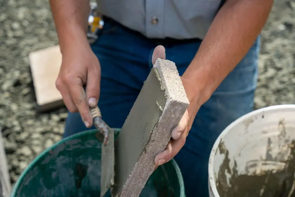 man applying refractory mortar to fireplace brickwork