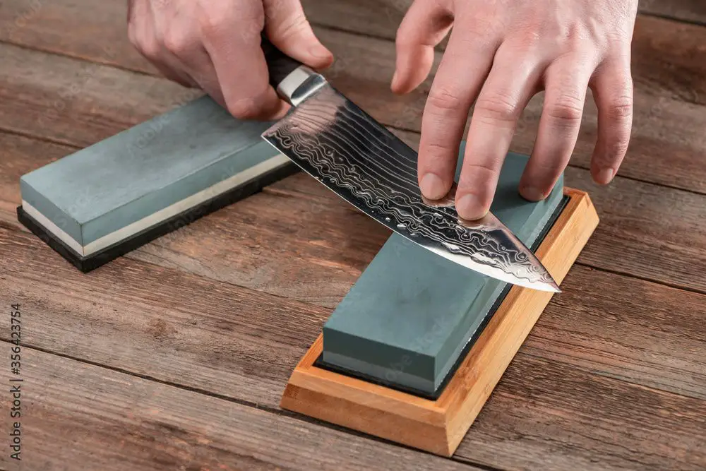 man sharpening knife on whetstone