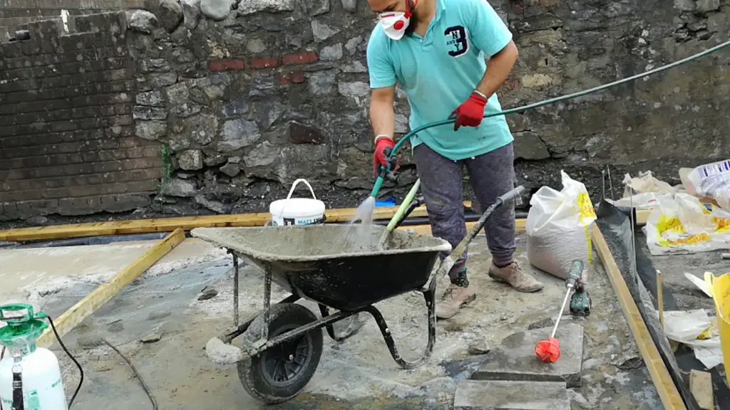 man using drill mixer to blend concrete