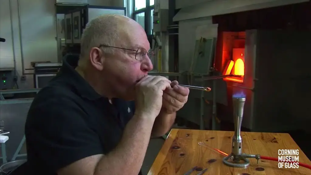 person blowing glass bubble with pipe