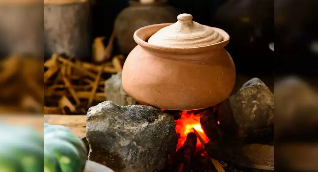 person cooking food in a clay pot