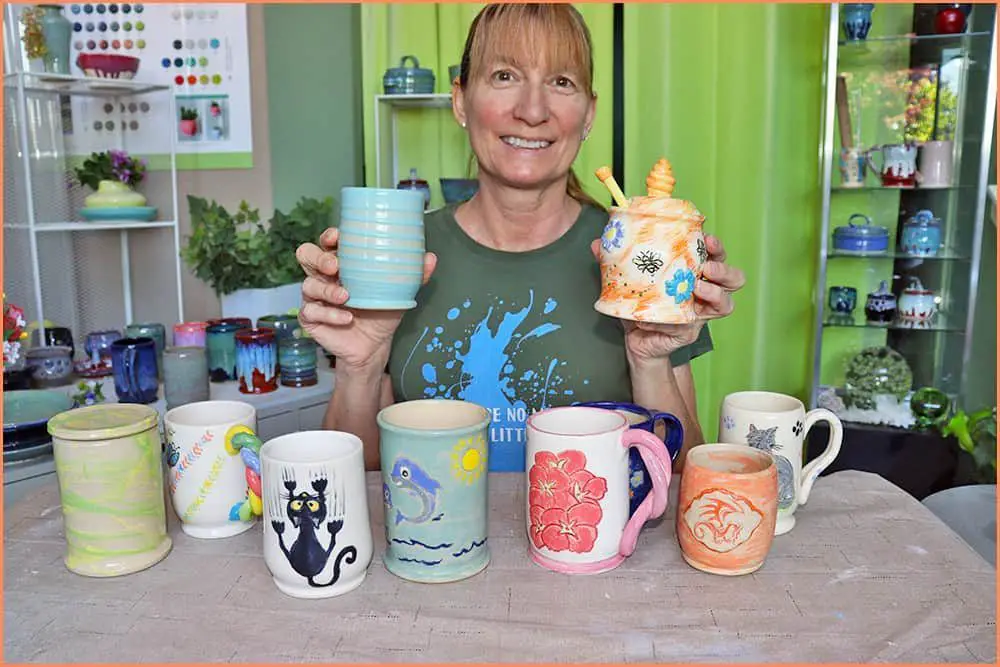 person decorating a ceramic mug with an underglaze pencil