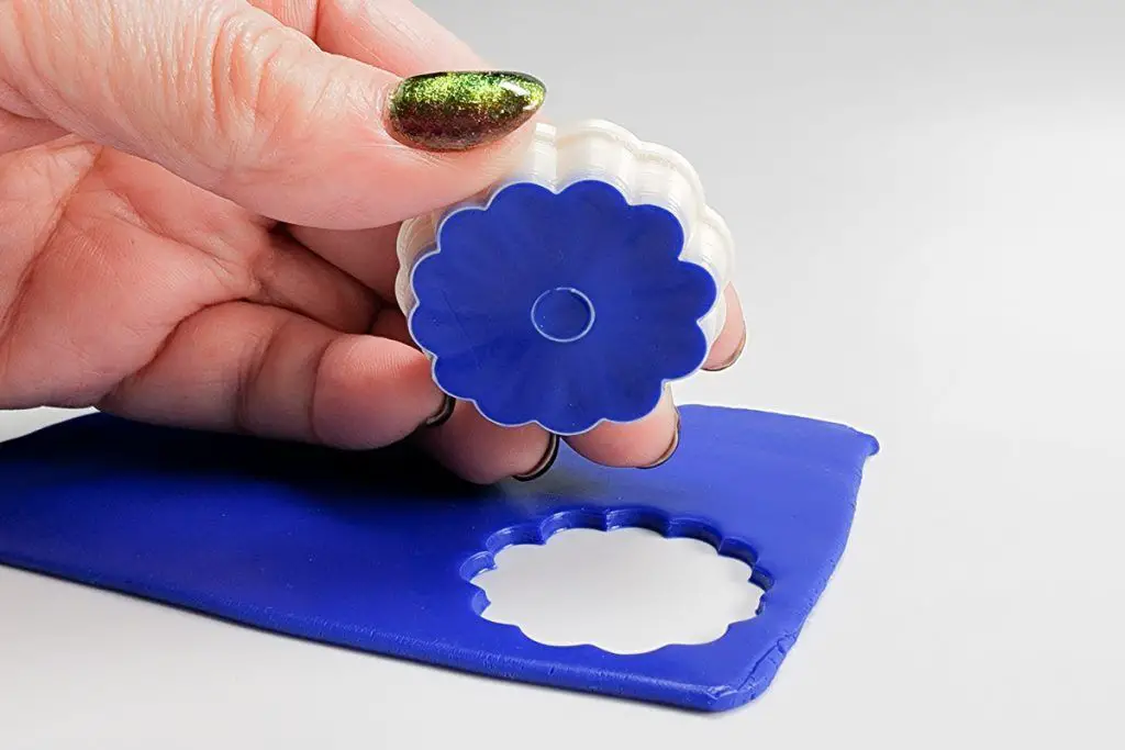 person dusting a cookie cutter with cornstarch to prevent polymer clay from sticking