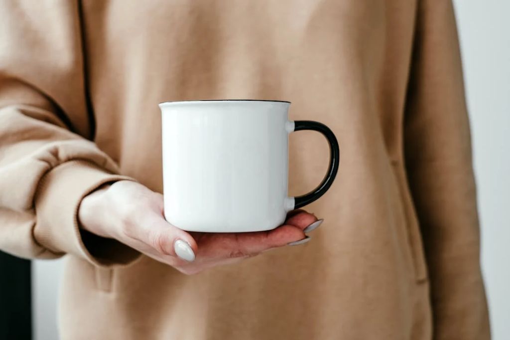 person holding ceramic coffee mug