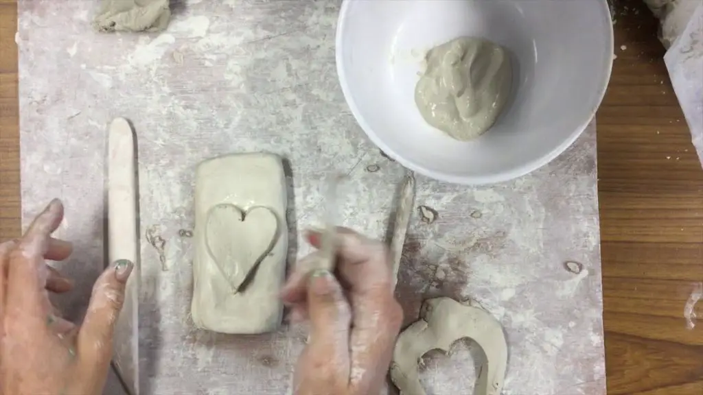 person joining clay pieces together to create pottery