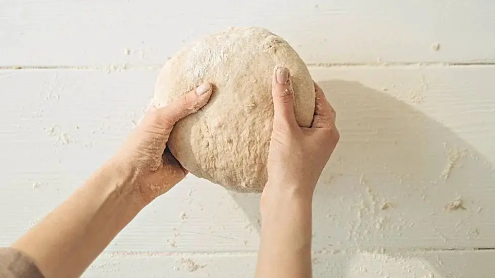 person kneading and shaping a ball of gray clay