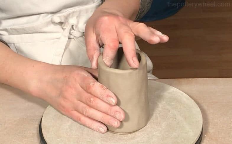 person pinching clay pot base on a table