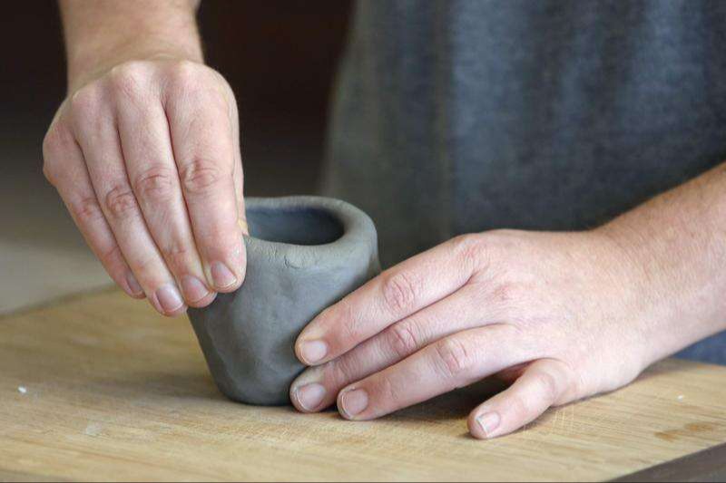 person pinching clay pottery by hand
