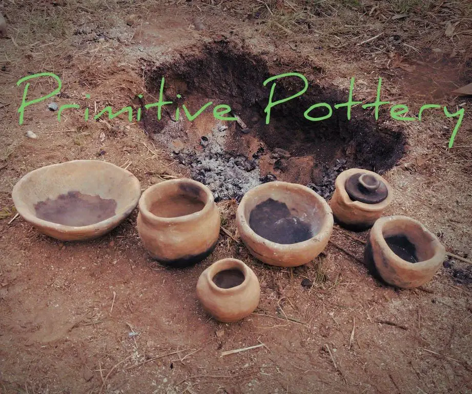 person placing clay pottery into a primitive fire pit.