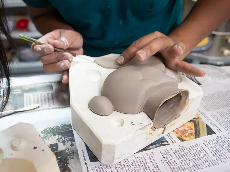 person pouring slip into plaster mold