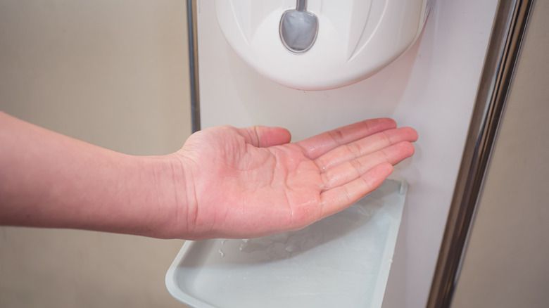 person refilling a soap dispenser