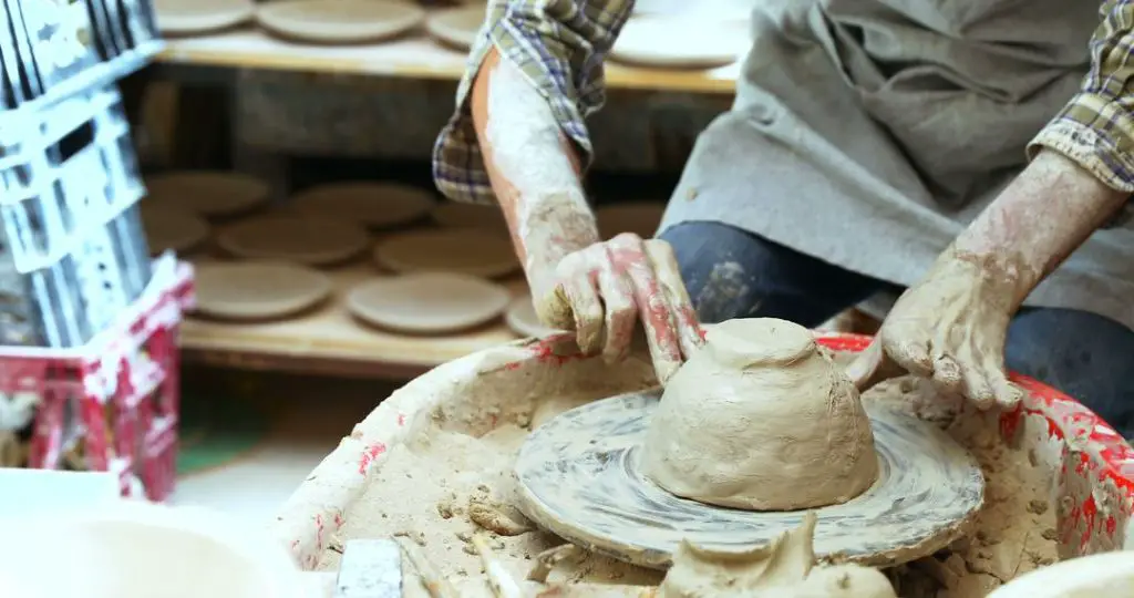 person shaping clay on a pottery wheel