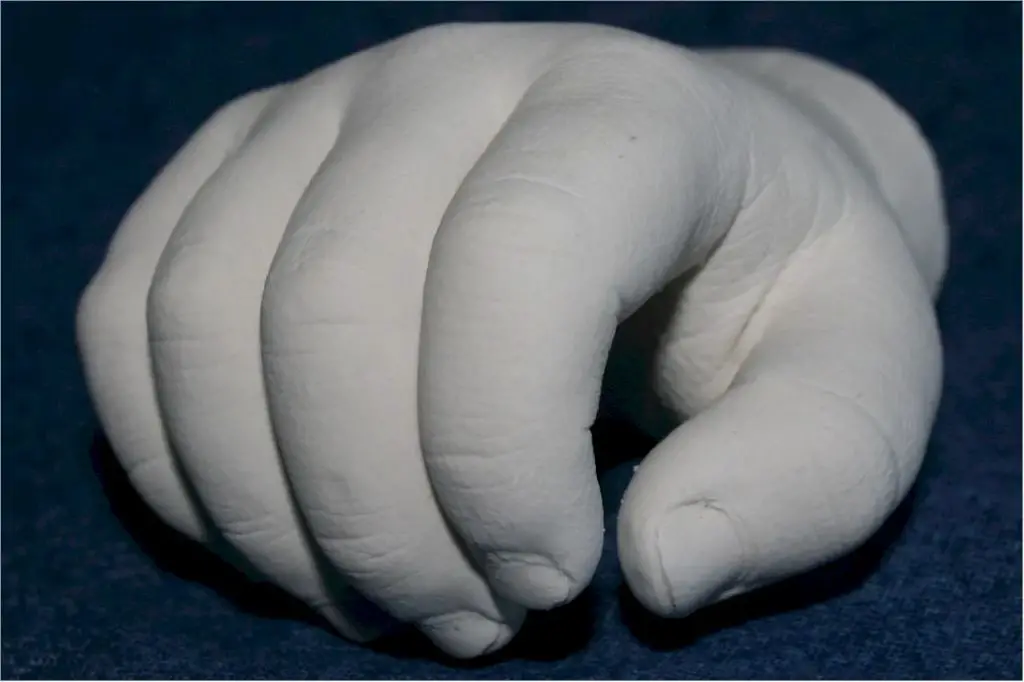 person shaping wet gray clay with their hands to create a mold