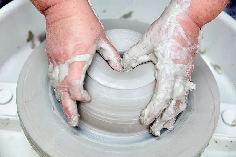 person throwing clay on a pottery wheel