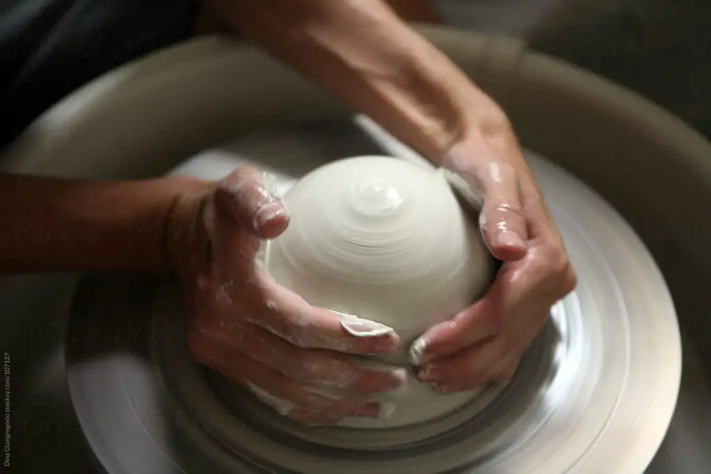 person using a pottery wheel to shape clay