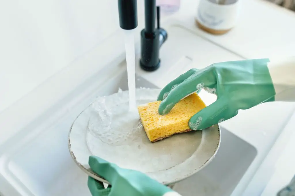 person using a yellow sponge to clean dishes