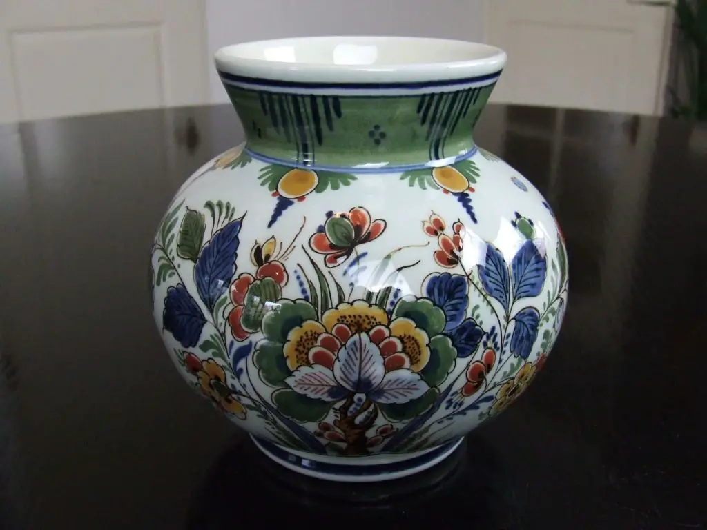 photo of antique delft vase from de porceleyne fles factory showing intricate hand-painted design and markings on base.