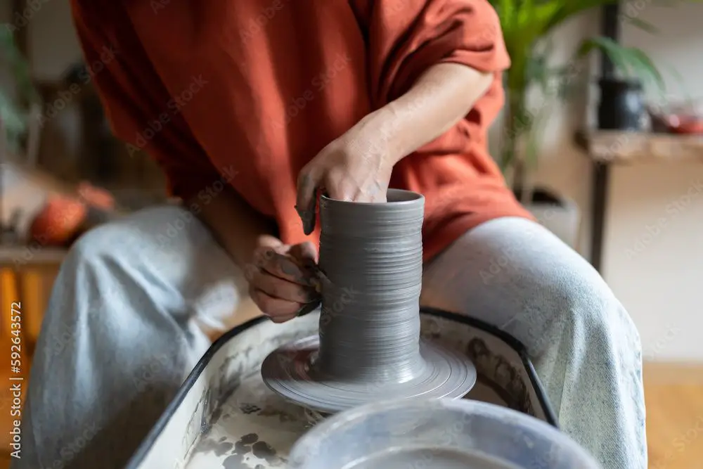 potter shaping clay on a rotating pottery wheel.