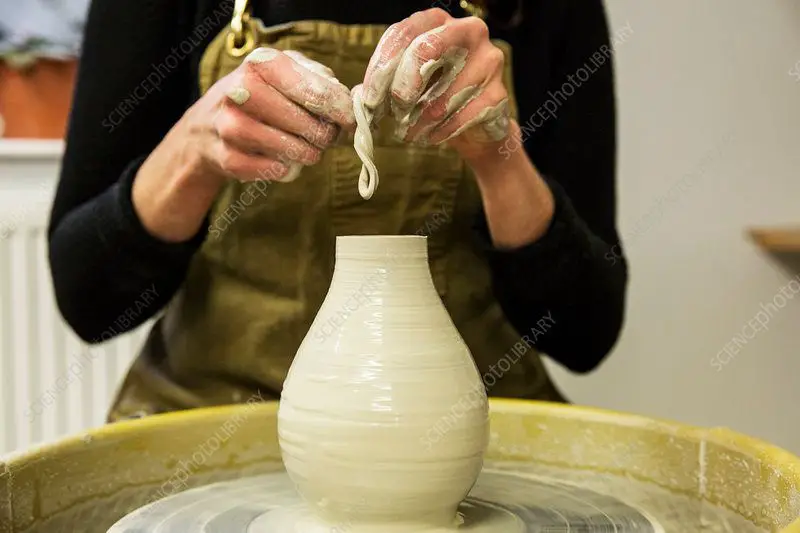 potter shaping clay vessel on wheel