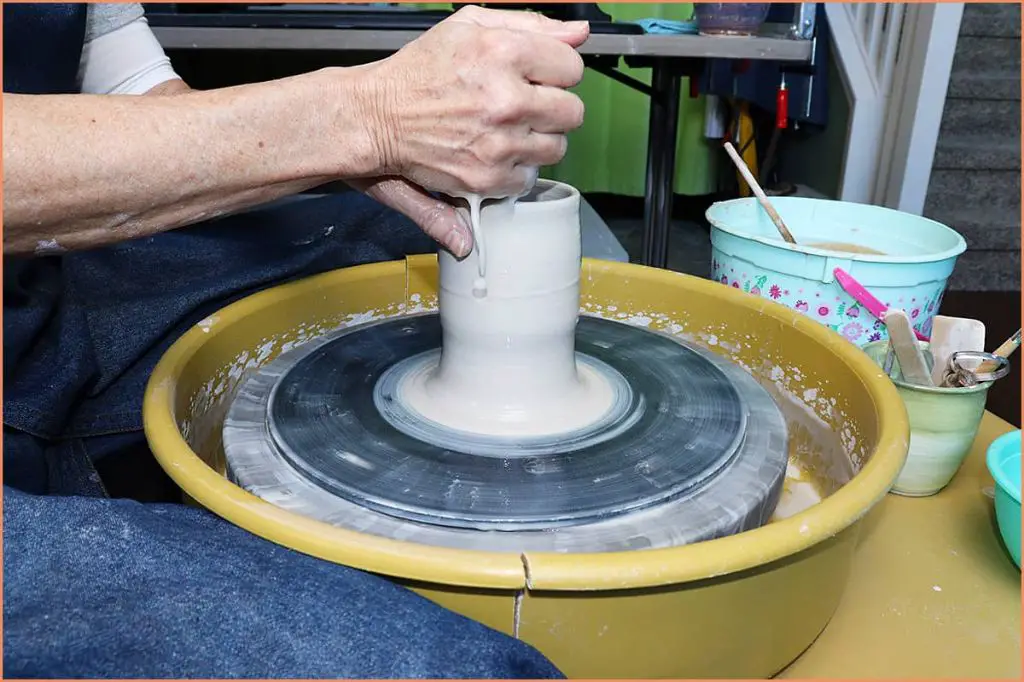 potter wiping throwing water from floor and wheel splash pan after throwing clay on a pottery wheel