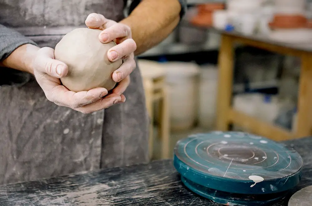 potters knead and wedge porcelain clay to remove air pockets and evenly distribute moisture for optimal plasticity.