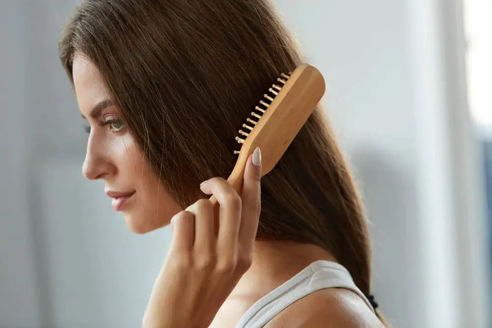 someone brushing their hair with a bamboo brush