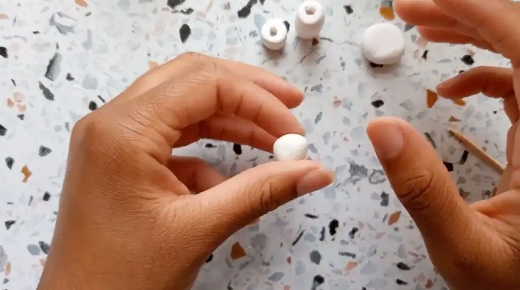 someone rolling a ball of polymer clay between their hands to form a smooth, round bead shape