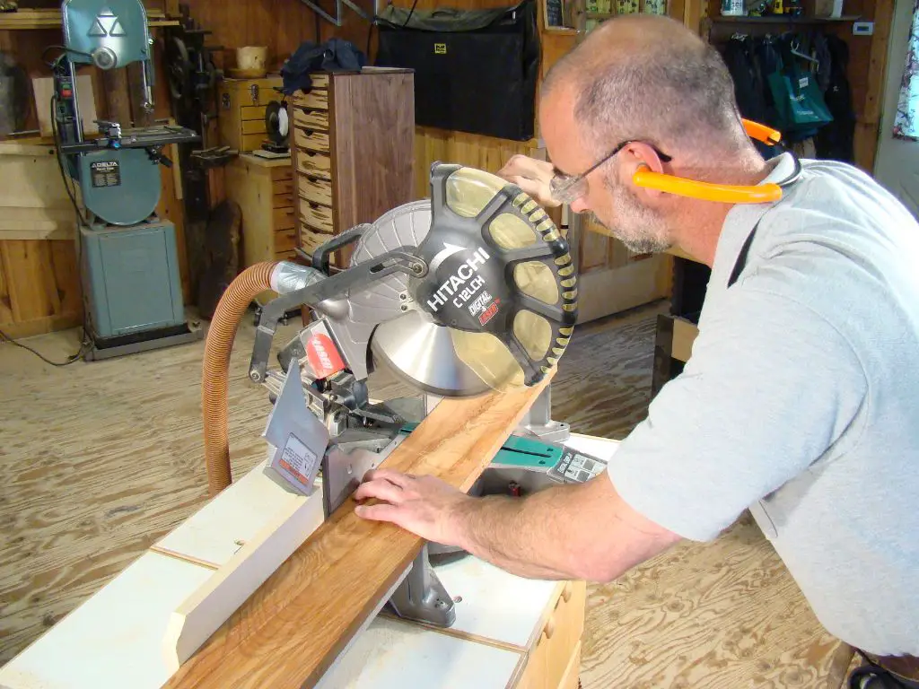 someone using a miter saw to cut a piece of wood