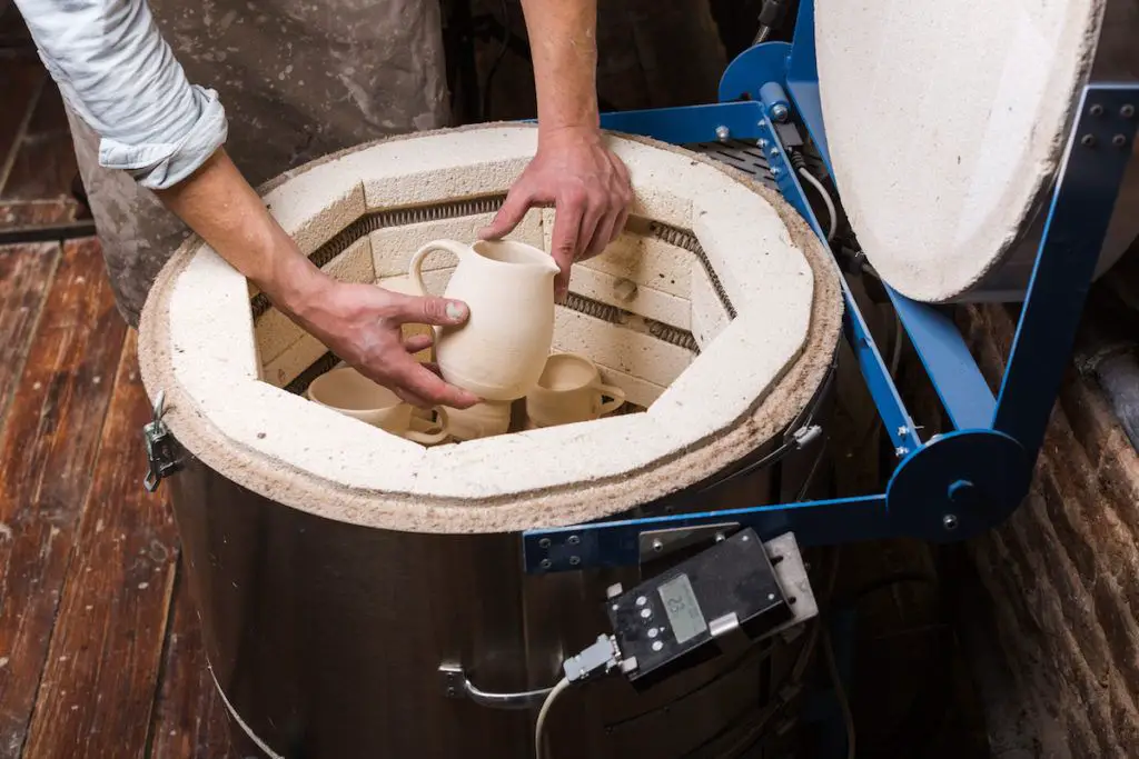someone using a small kiln to create pottery