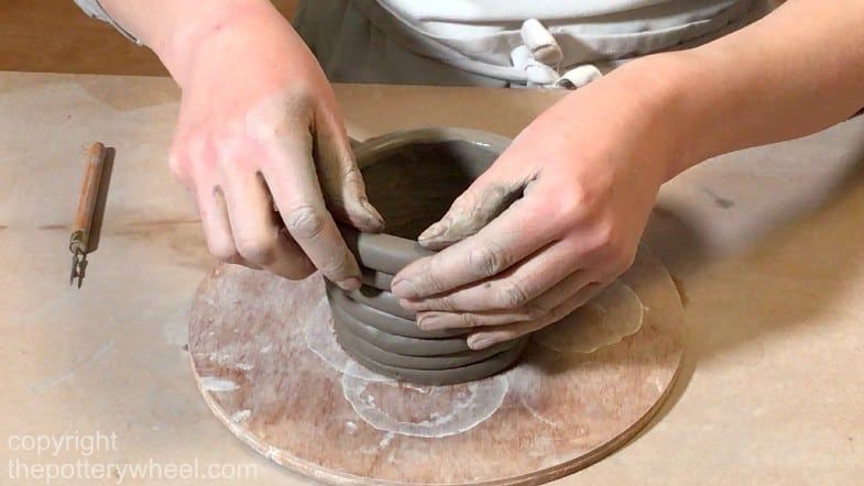 someone using clay handbuilding techniques to create a pottery piece without a wheel