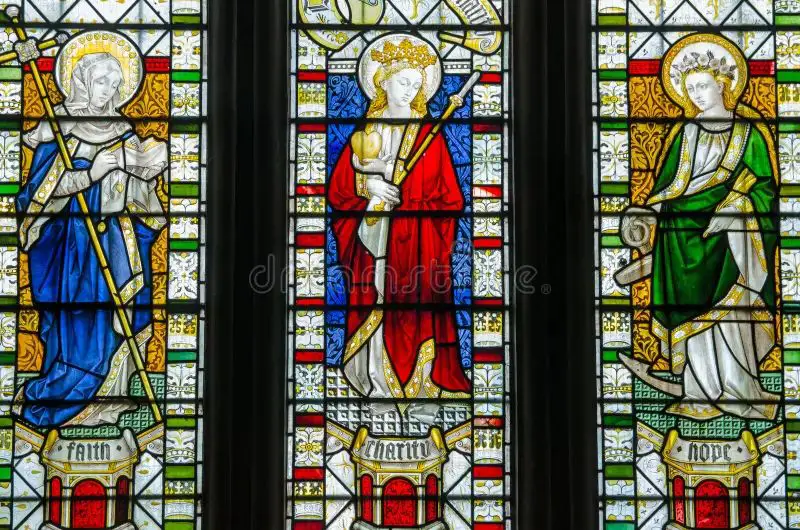 stained glass image of three french hens representing the three theological virtues of faith, hope and charity