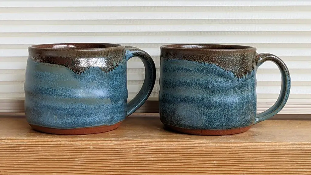 two handcrafted stoneware coffee mugs glazed in earthy blue and brown tones