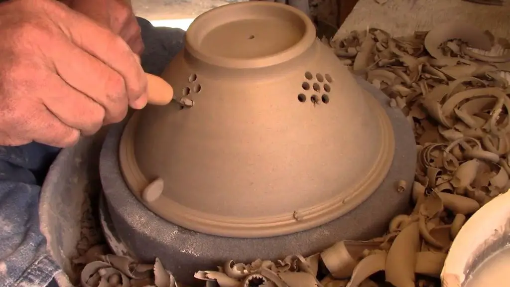 using a wooden skewer to gently scrape clay pieces out of the holes and gaps of a clay cutter