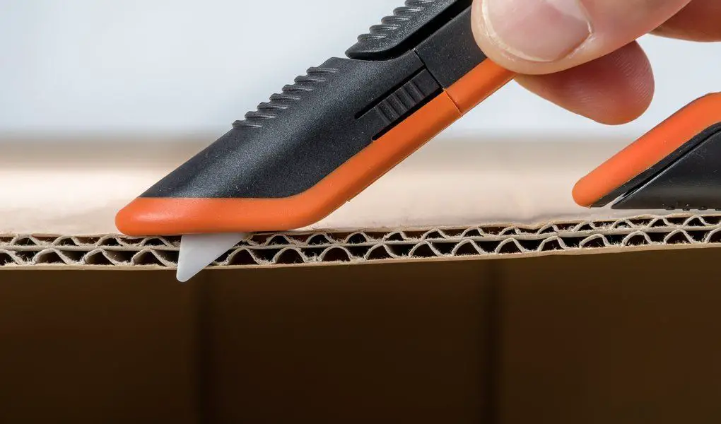 using box cutter to slice cardboard