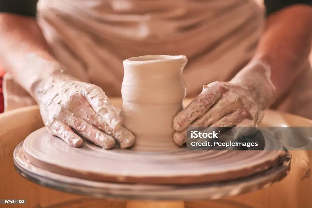 using hands and tools to shape spinning clay.