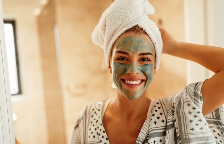 woman applying a bentonite clay facial mask