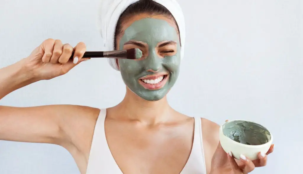 woman applying a clay face mask