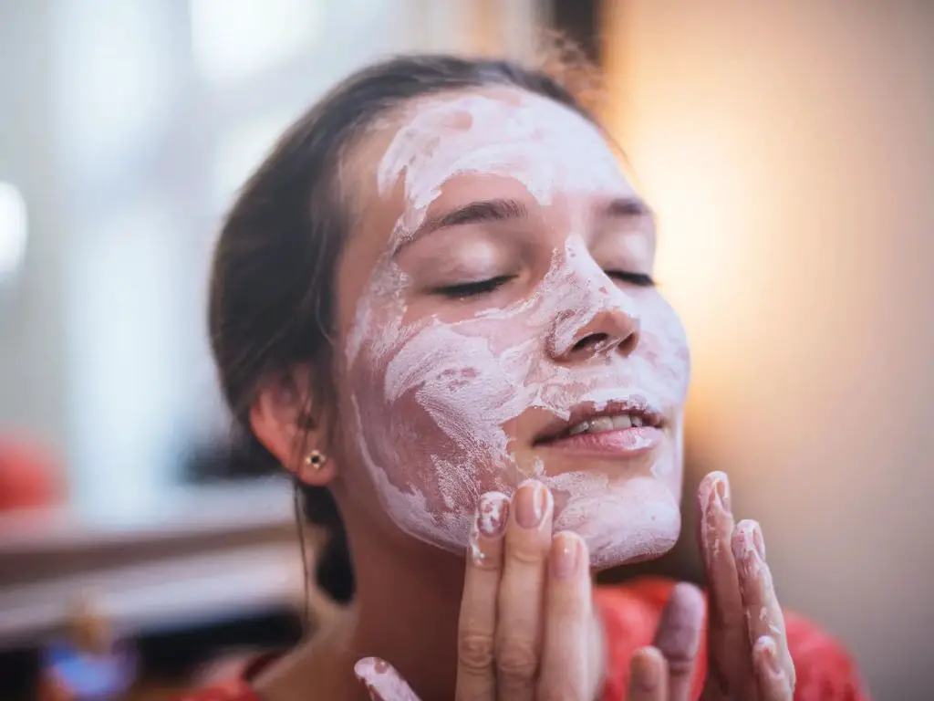 woman applying aztec clay mask to her face