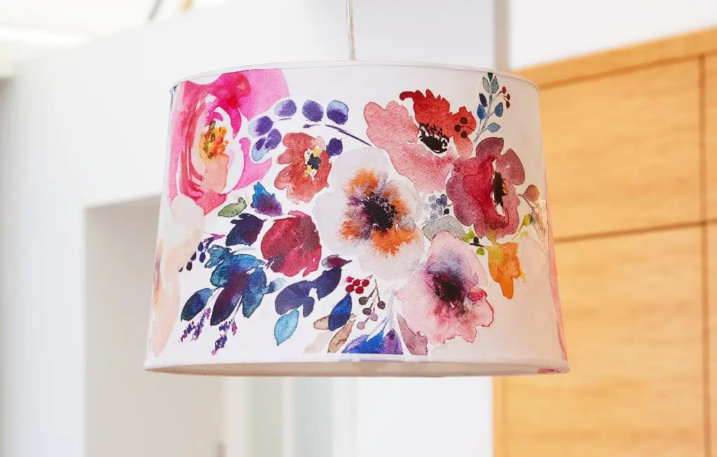 woman painting a lamp shade with flowers