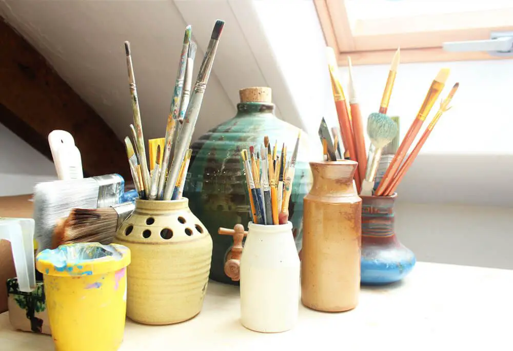 workspace with pottery, paints and brushes organized