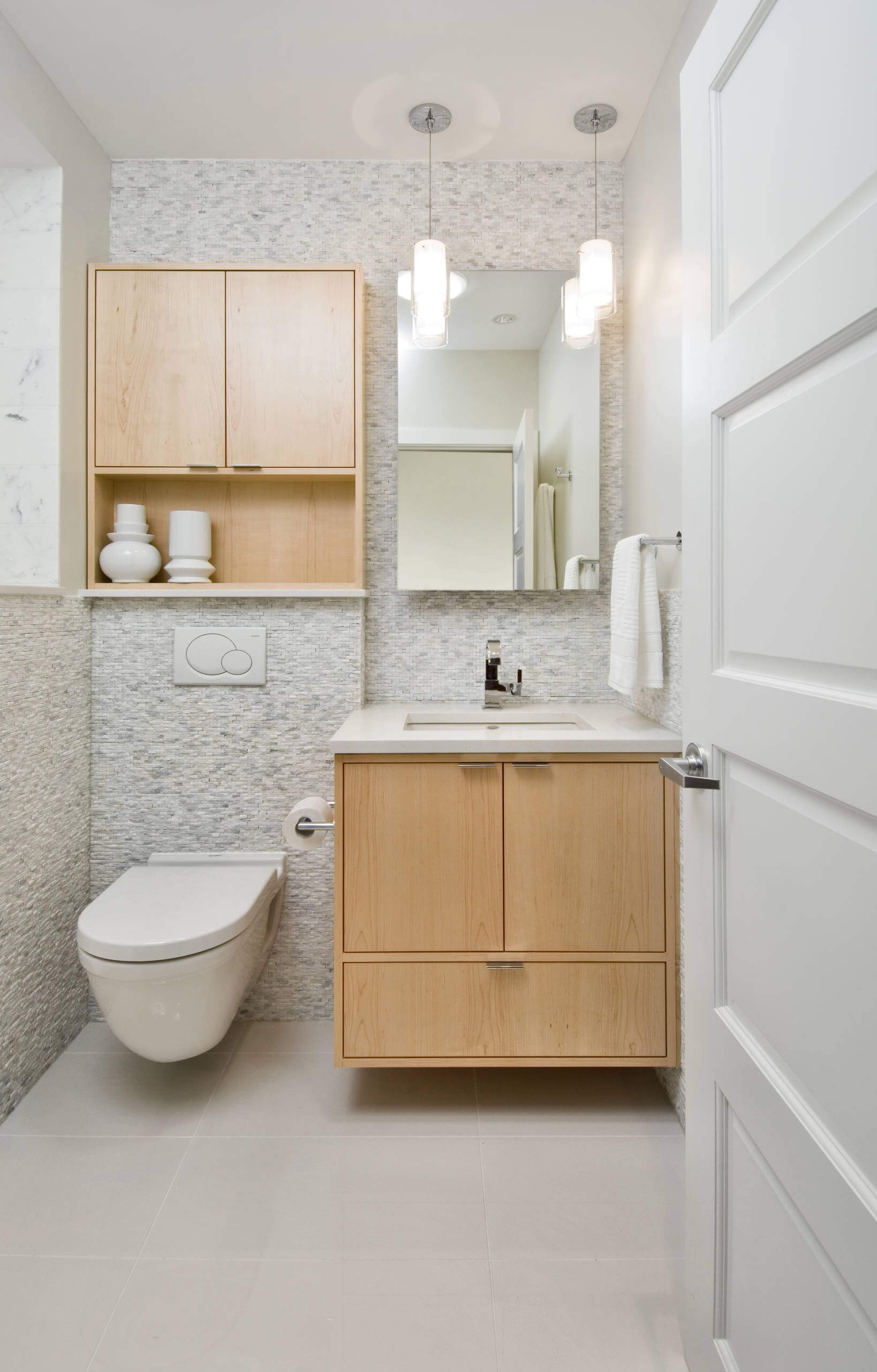 #6. Small trendy white tile and stone tile porcelain floor bathroom with an undermount sink, flat-panel cabinets, light wood cabinets, a wall-mount toilet and gray walls