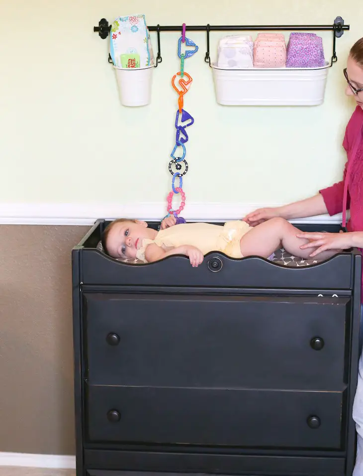 Place baby diapers in aluminum pots hanging on a curtain rail