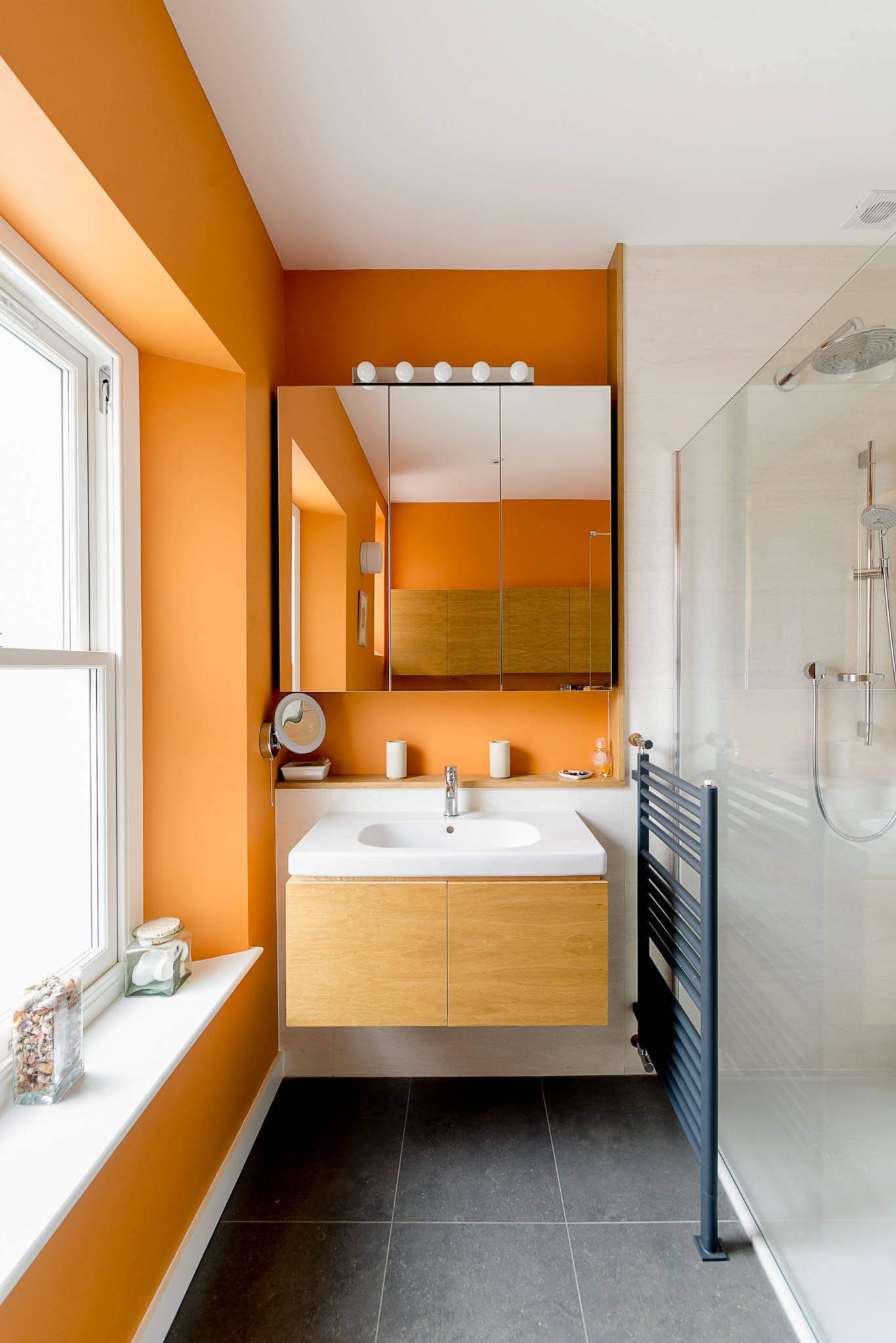 #20. Trendy gray floor bathroom with orange walls