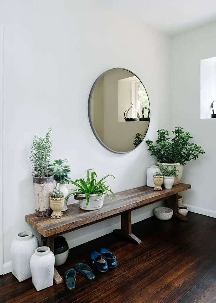 Round mirror above a bench with planters